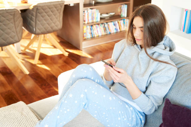 istock Beautiful young woman text messaging while sitting on sofa at home 1124761847
