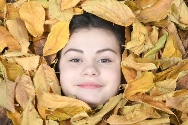 Face of little smile girl on the background of autumn leaves
