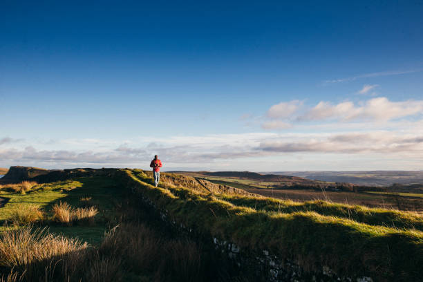 One young adult standing on Hadrian's Wall in Northumberland, UK countryside.