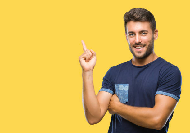 istock Young handsome man over isolated background with a big smile on face, pointing with hand and finger to the side looking at the camera. 1124772523