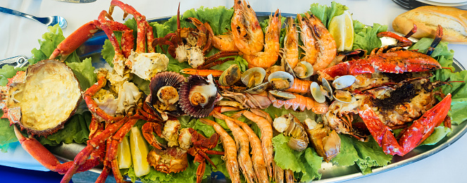 Assortment of grilled seafood with prawns, lobster, clams, crayfish, scallops, spider crab, small crabs and lemon. Delicious