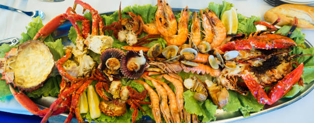 Assortment of grilled seafood with prawns, lobster, clams, crayfish, scallops, spider crab, small crabs and lemon. Delicious stock photo