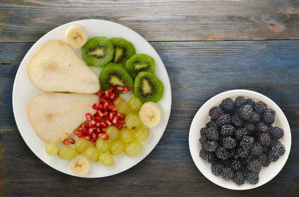 istock fruit mix (pear, kiwi, grapes, banana, pomegranate) on a wooden background 1124782110