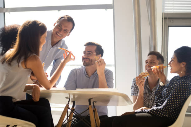 istock Colleagues eating pizza during lunch sitting together in office 1124783314