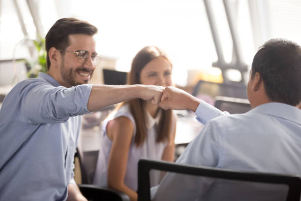 istock Colleagues fist bumping sitting on chairs at workplace 1124783344