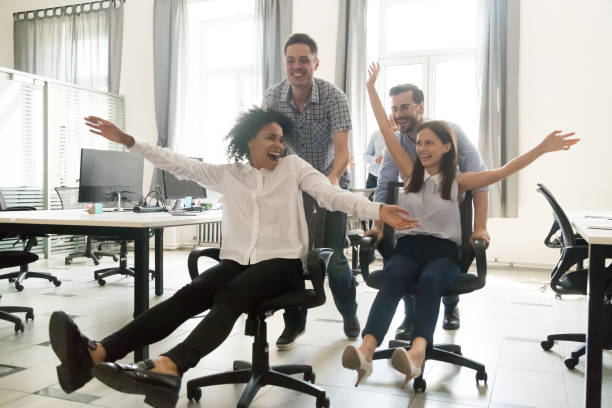 istock Workers having fun riding in office chairs in coworking space 1124783352