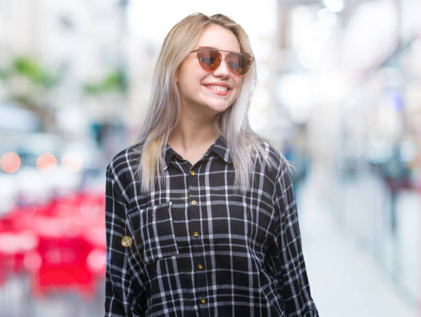 istock Young blonde woman wearing sunglasses over isolated background looking away to side with smile on face, natural expression. Laughing confident. 1124794708