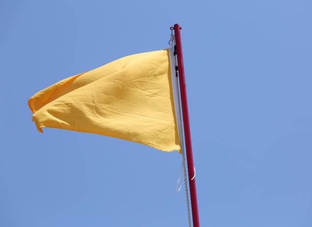 istock yellow flag waving in the blue sky as a warning 1124800144