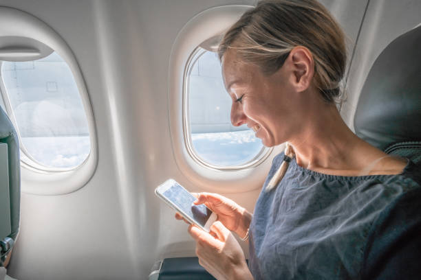 istock Young woman in airplane using mobile phone during flight 1124800153
