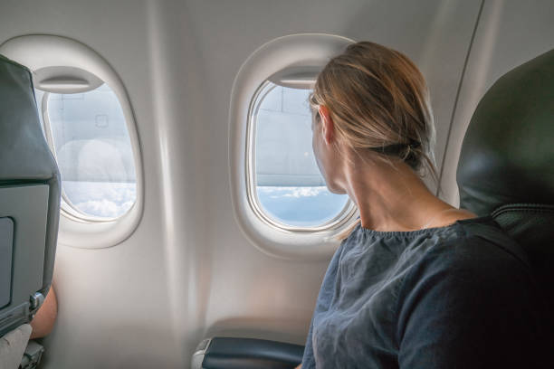 istock Young woman in airplane looking through window 1124800164