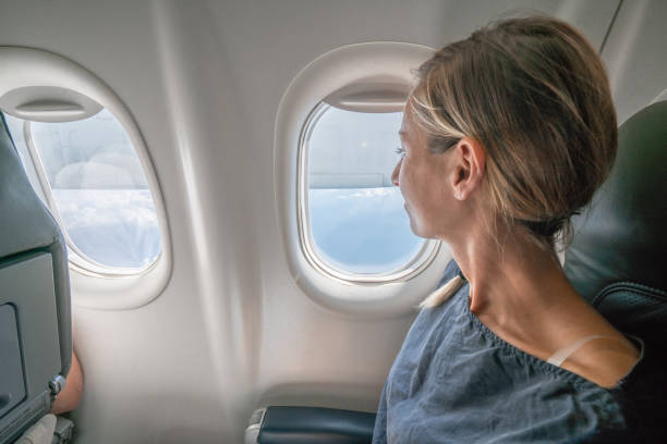 Young woman in airplane looking through window