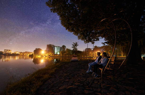 istock Man and woman having a rest on shore under night sky 1124801505