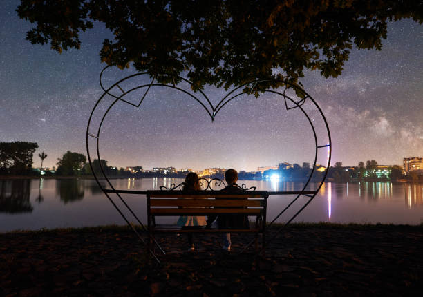 Man and woman having a rest on shore under night sky
