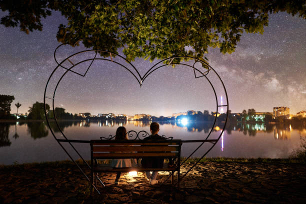 istock Man and woman having a rest on shore under night sky 1124801507
