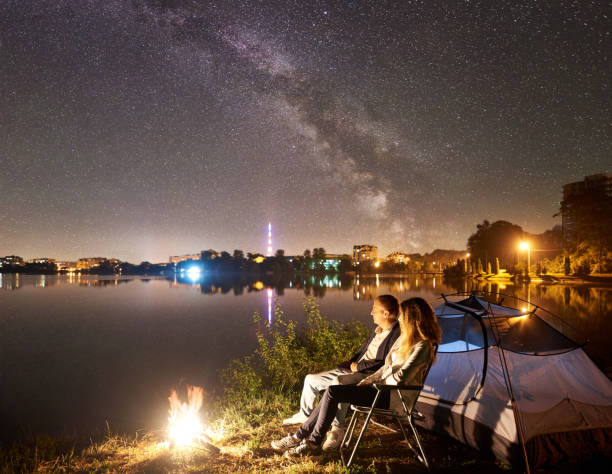 istock Man and woman having a rest on shore under night sky 1124801511