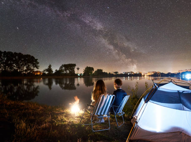 istock Man and woman having a rest on shore under night sky 1124801516