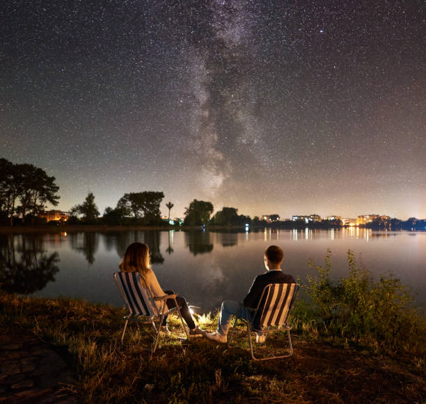 istock Man and woman having a rest on shore under night sky 1124801522