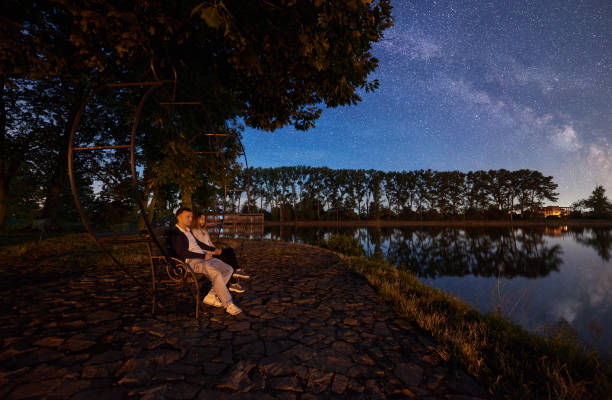 istock Man and woman having a rest on shore under night sky 1124801523