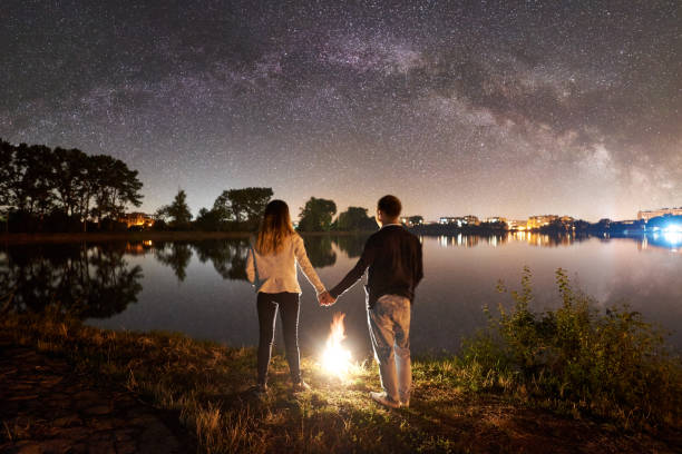 Man and woman having a rest on shore under night sky
