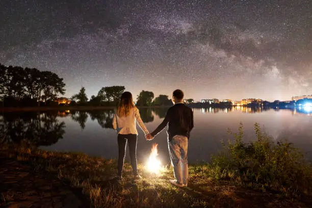 Photo of Man and woman having a rest on shore under night sky