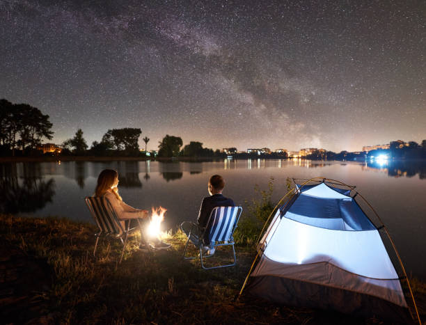 istock Man and woman having a rest on shore under night sky 1124801527