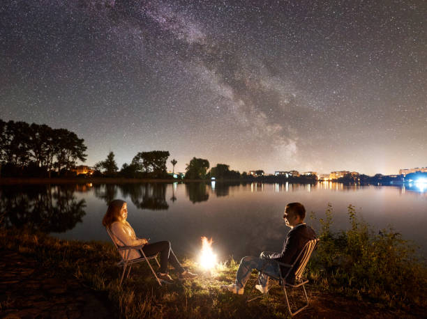 istock Man and woman having a rest on shore under night sky 1124801541