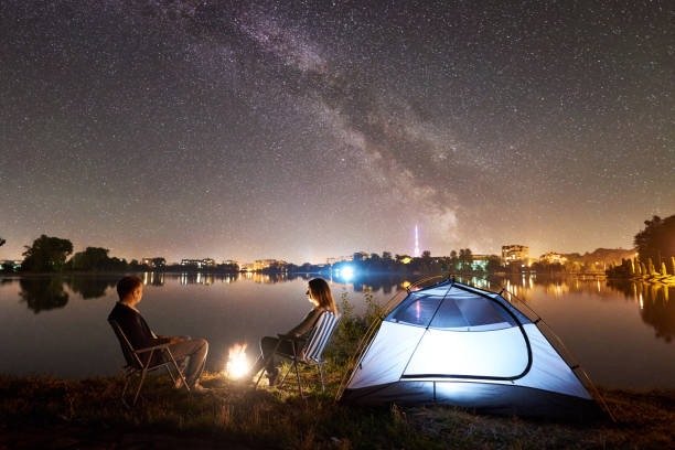 istock Man and woman having a rest on shore under night sky 1124801546