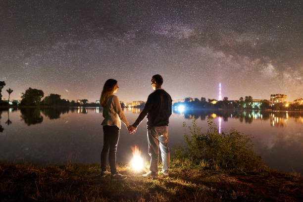 istock Man and woman having a rest on shore under night sky 1124801552