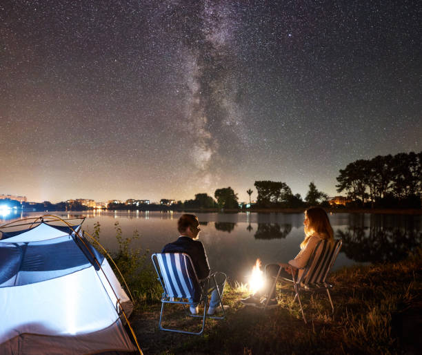 istock Man and woman having a rest on shore under night sky 1124801556