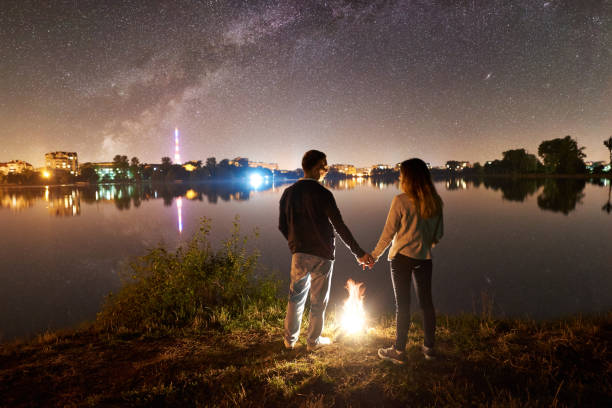 istock Man and woman having a rest on shore under night sky 1124801565