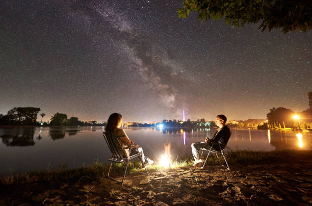 istock Man and woman having a rest on shore under night sky 1124801573