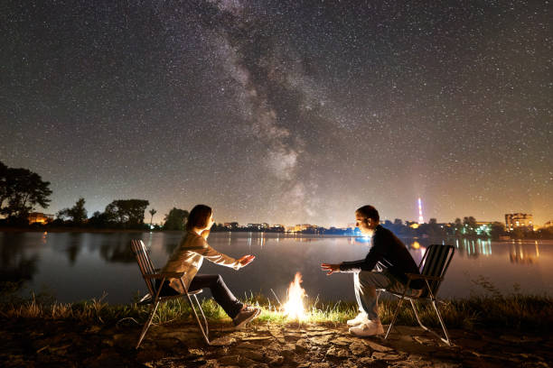 istock Man and woman having a rest on shore under night sky 1124801582