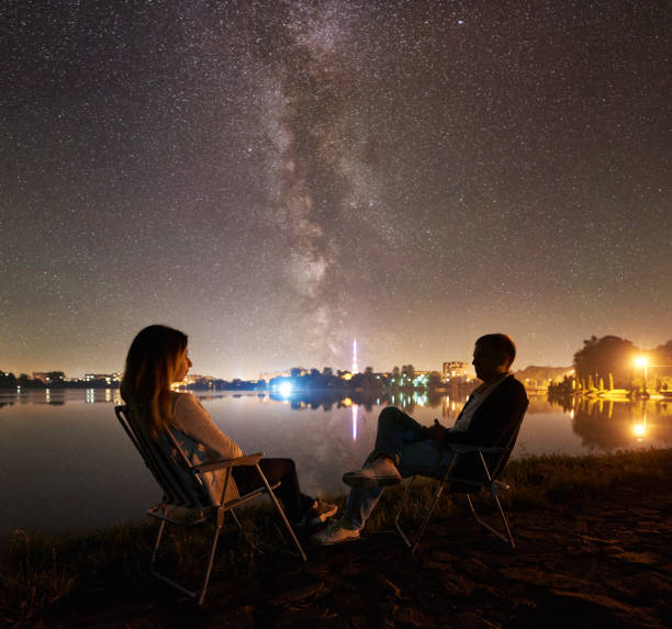 istock Man and woman having a rest on shore under night sky 1124801584