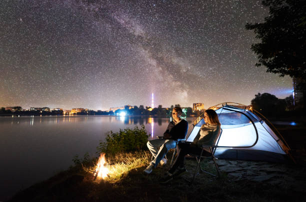 istock Man and woman having a rest on shore under night sky 1124801587