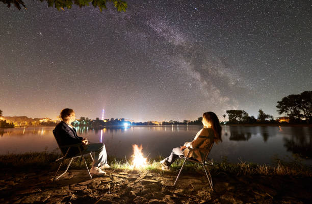 istock Man and woman having a rest on shore under night sky 1124801594