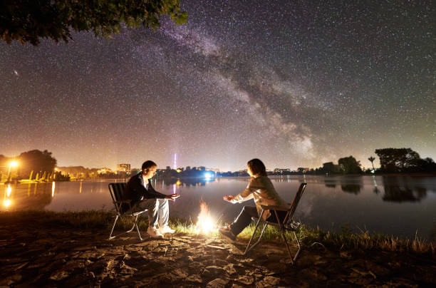 istock Man and woman having a rest on shore under night sky 1124801601