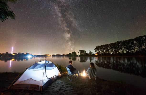 istock Man and woman having a rest on shore under night sky 1124801606