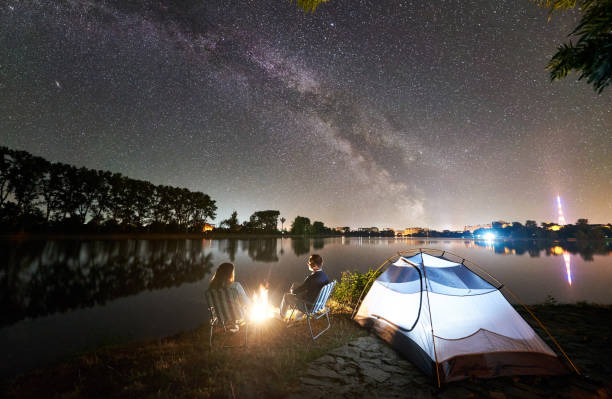 istock Man and woman having a rest on shore under night sky 1124801608