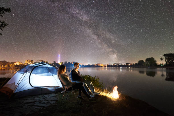 istock Man and woman having a rest on shore under night sky 1124801610