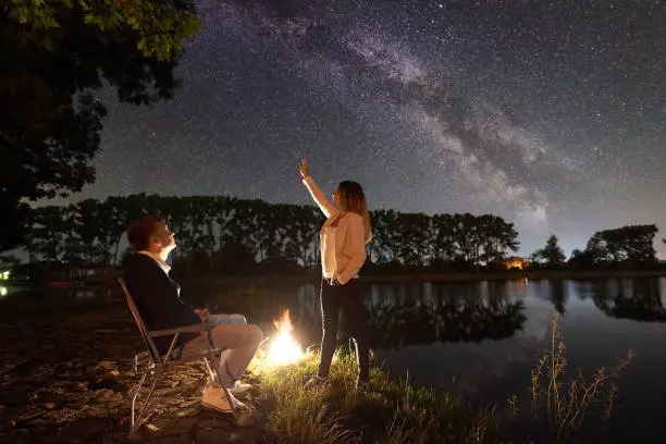 Photo of Man and woman having a rest on shore under night sky