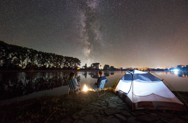 istock Man and woman having a rest on shore under night sky 1124801621