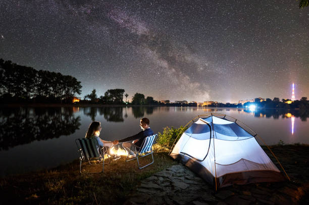 istock Man and woman having a rest on shore under night sky 1124801623