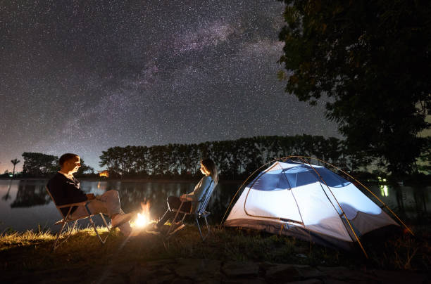 istock Man and woman having a rest on shore under night sky 1124801624