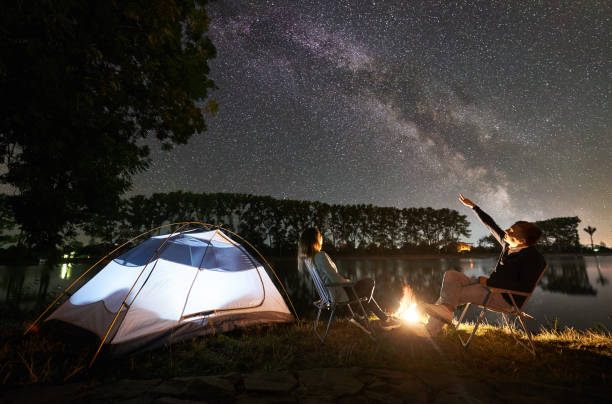 istock Man and woman having a rest on shore under night sky 1124801626