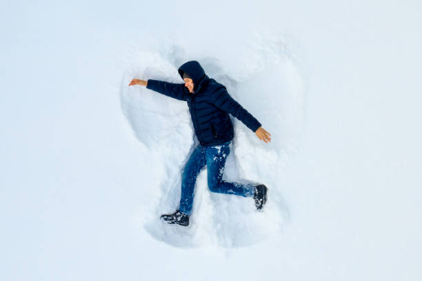istock Conceptual image of boy runnin lying down on the ground covered with snow isolated on white, top view from drone 1124804954