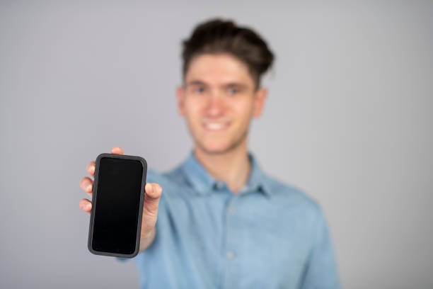 istock Millennial holding out a mobile phone with blank screen 1124806584