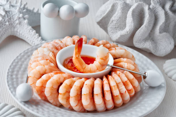 Close-up on shrimp ring with sweet chili sause on light table with white sea decorations Close-up on shrimp ring with sweet chili sause on light background with white sea decorations shell starfish orange sea stock pictures, royalty-free photos & images