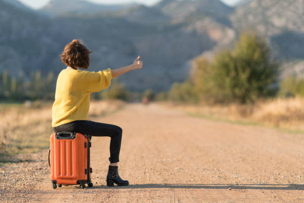 istock Young woman with suitcase hitchhiking 1124820864