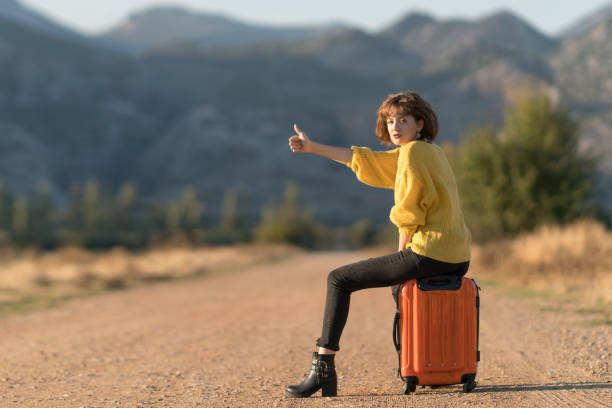 istock Young woman with suitcase hitchhiking 1124821371