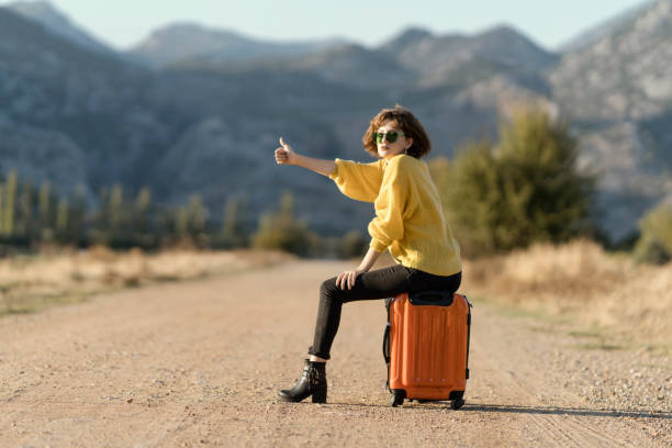istock Young woman with suitcase hitchhiking 1124821743